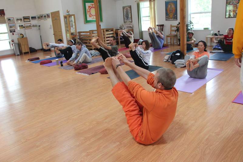 Students practice Yoga asana as the teacher demonstrates.