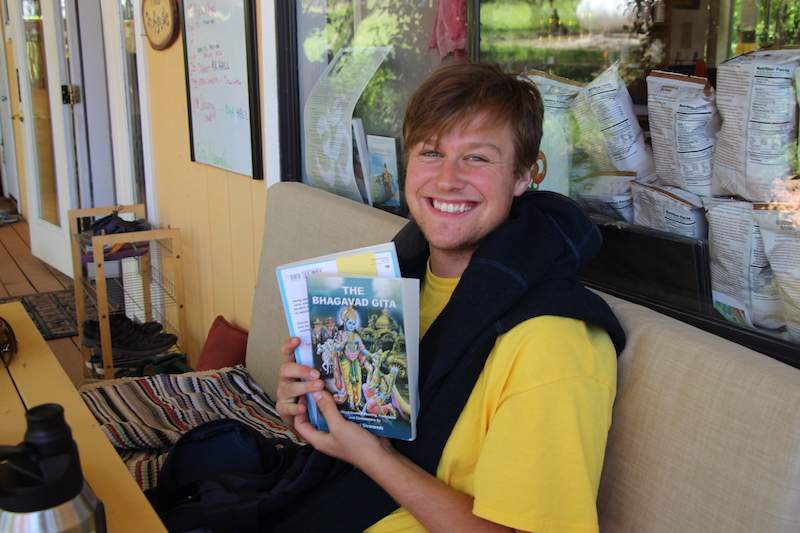 student smiling with books in hand for the course
