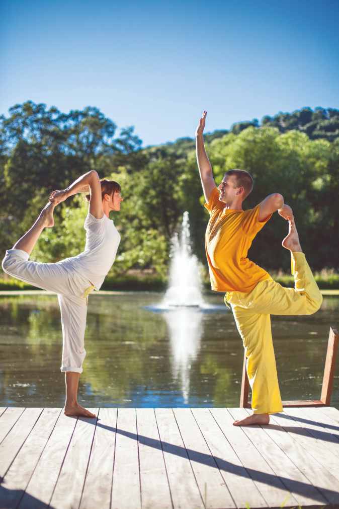 Two students practice the Yoga Pose called Nataraj.