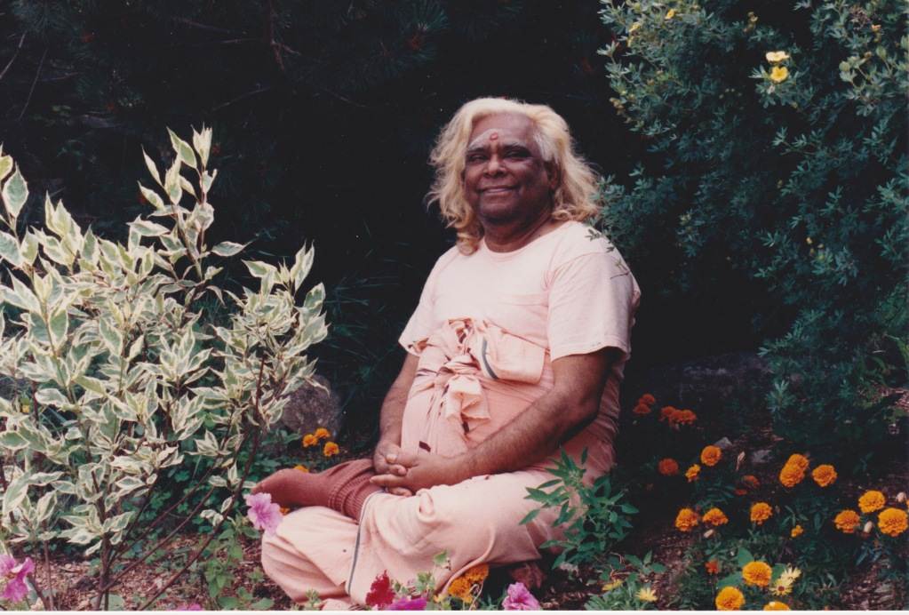Swami Vishnu sitting and smiling in nature with flowers