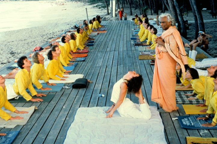 Swami Vishnudevananda teaches a yoga class with many students practicing cobra.