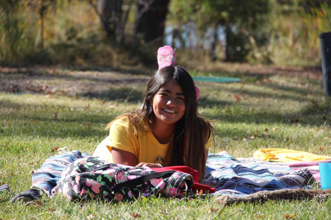Student smiling while laying on a blanket on the grass 