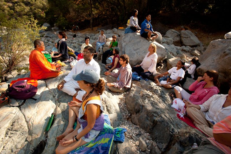 Many people meditating sitting on rocks
