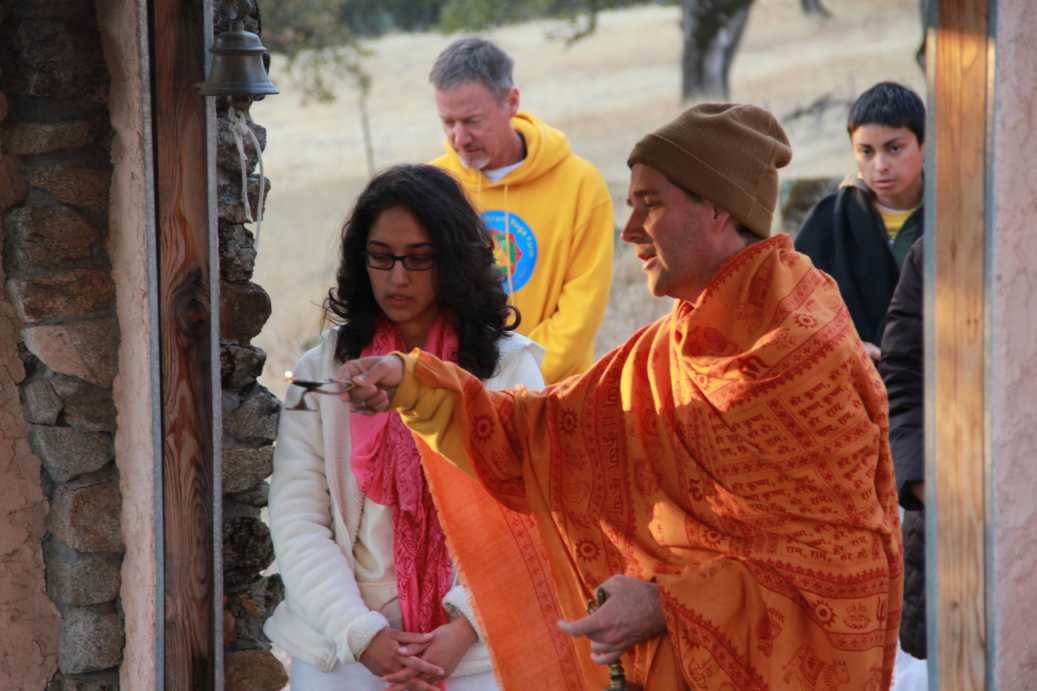 Swami waving arati lamp at Siva temple