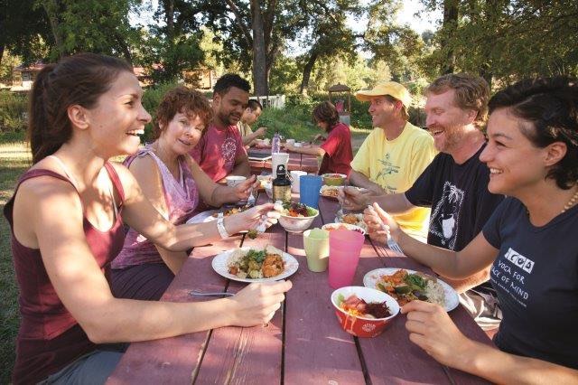 Groups of people at 2 picnic tables laughing and enjoying an organic ayurvedic lunch
