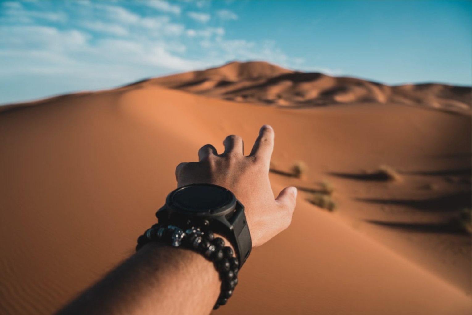 A hand reaches out in the dry desert full of sand.